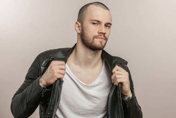young trendy man in leather black jacket posing to the camera - Foto, imagen