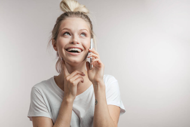 Beautiful smiling blond woman talking by cell mobile phone. Closeup. Isolated. - 写真・画像