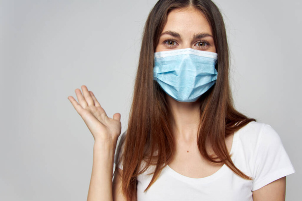 Женщина в медицинской маске на лице смотрит вперед  - Фото, изображение