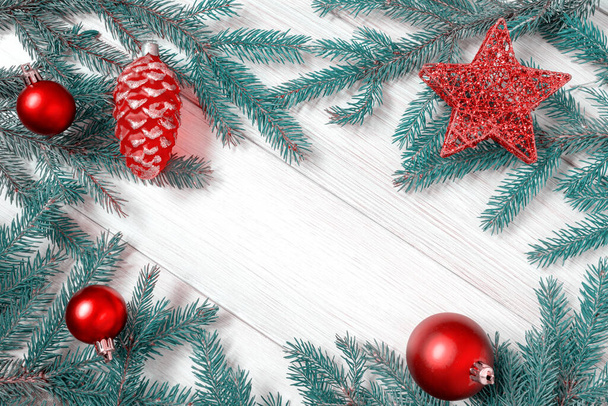 Weihnachts- oder Neujahrsschmuck Hintergrund: Zweige, rotes Weihnachtsspielzeug auf weißem Holzbrett. Kopierraum. Getönte - Foto, Bild