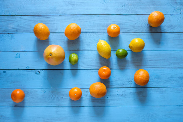Whole citrus assorty on the middle of blue wooden textured background. Top view. - Foto, Bild