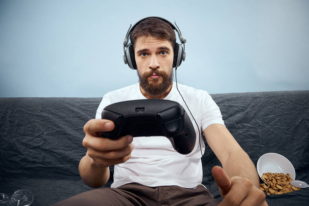 Muž sedí na pohovce nosí sluchátka s gamepad hraje jídlo volnočasové technologie životní styl - Fotografie, Obrázek