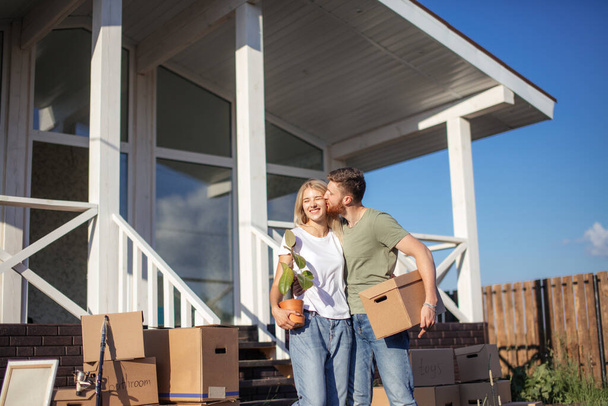 Husband and wife standing in front of new buying home with boxes - Foto, Imagem