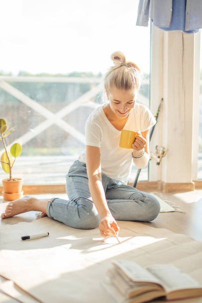 woman sitting on floor of new house planning home on paper. - Foto, imagen