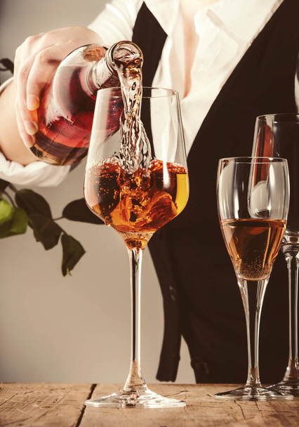 Sommelier pouring rose wine into glass at wine tasting in winery, bar or restaurant. White background - Foto, afbeelding