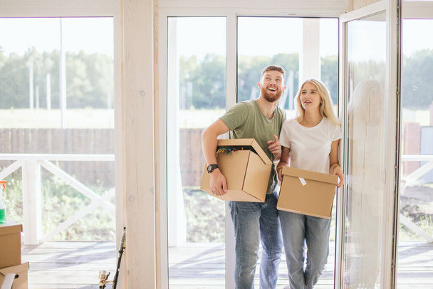 Happy Couple Carrying Cardboard Boxes Into New Home On Moving Day - Foto, afbeelding