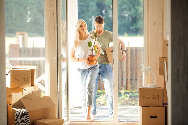 Happy Couple Carrying Cardboard Boxes Into New Home On Moving Day - Foto, afbeelding