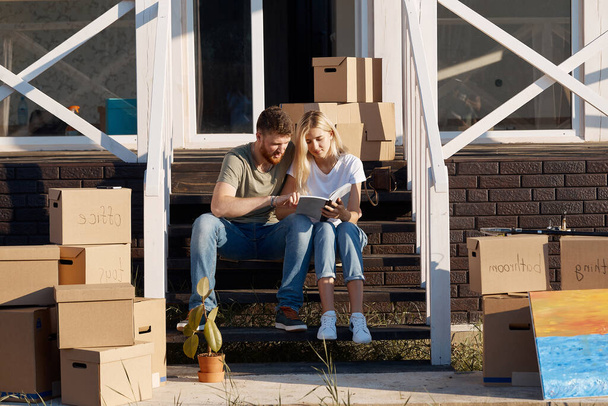 Husband and wife standing in front of new buying home with boxes - Fotografie, Obrázek