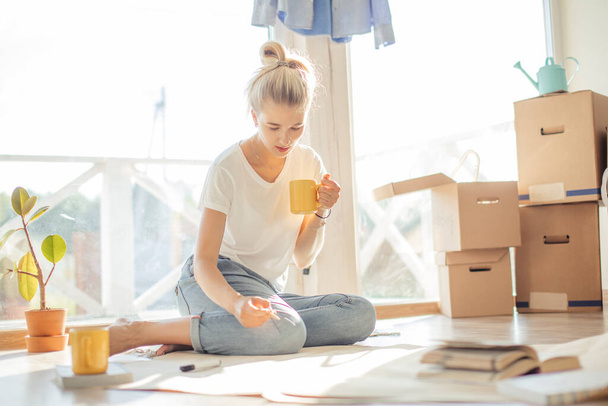 woman sitting on floor of new house planning home on paper. - Photo, Image
