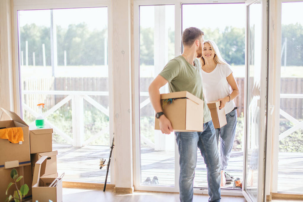 Happy Couple Carrying Cardboard Boxes Into New Home On Moving Day - Photo, Image