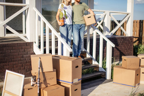 Husband and wife standing in front of new buying home with boxes - Foto, Imagem