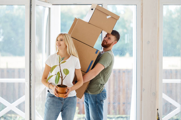 Happy Couple Carrying Cardboard Boxes Into New Home On Moving Day - Photo, image