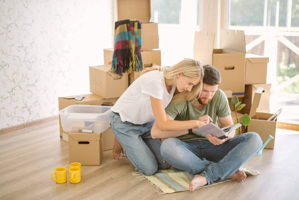 couple with book sitting on bed while moving into new home - Φωτογραφία, εικόνα