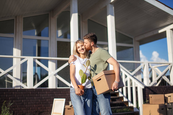 Husband and wife standing in front of new buying home with boxes - Foto, immagini