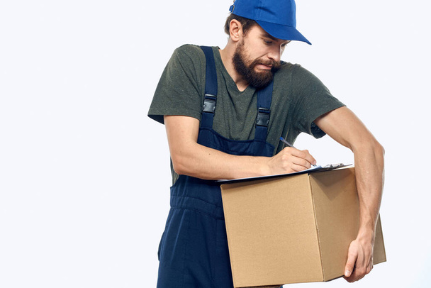 Man in working uniform box delivery loader courier light background - Photo, Image