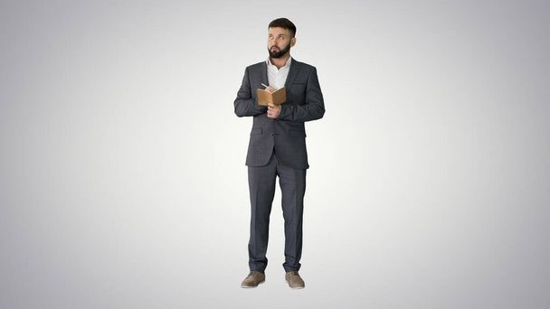 Soustředěný mladý muž ve formalwear drží poznámkový blok a psaní - Fotografie, Obrázek