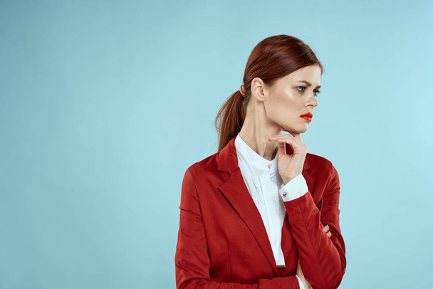 Elegante Frau in roter Jacke hell Make-up Lippen Selbstbewusstsein beschnitten Ansicht blauer Hintergrund - Foto, Bild
