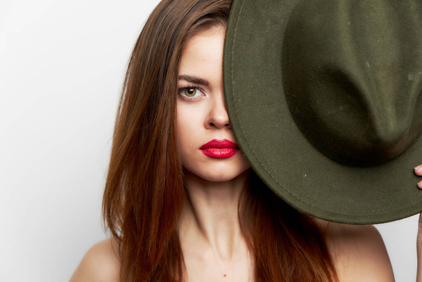Mujer sosteniendo sombrero cubre su cara desnuda hombros cerca de la cara labios rojos  - Foto, imagen