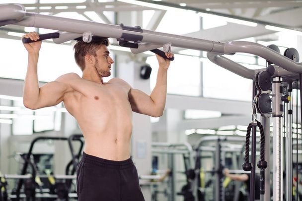 bodybuilder performing exercise with gym training mashine - Photo, image