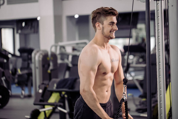 bodybuilder performing exercise with gym training mashine - Fotografie, Obrázek