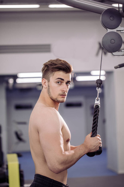 bodybuilder performing exercise with gym training mashine - Foto, immagini