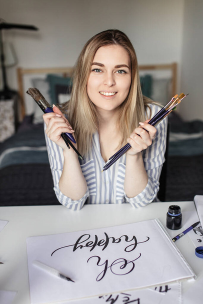 blonde girl writes with brush and ink, lettring process - Photo, image
