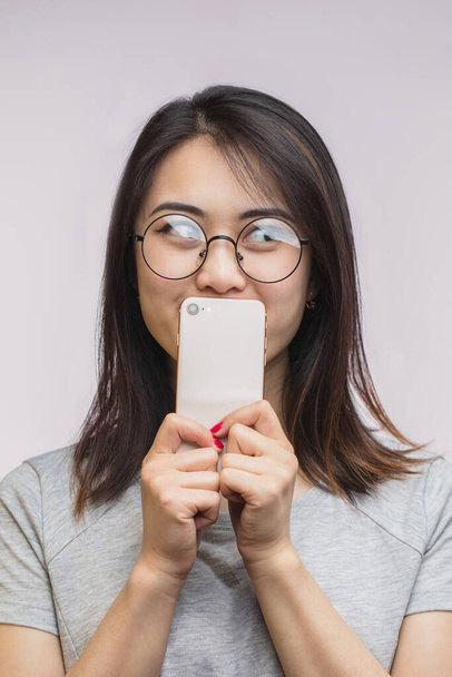 Asian woman holding modern smart phone isolated over white background in studio - Valokuva, kuva
