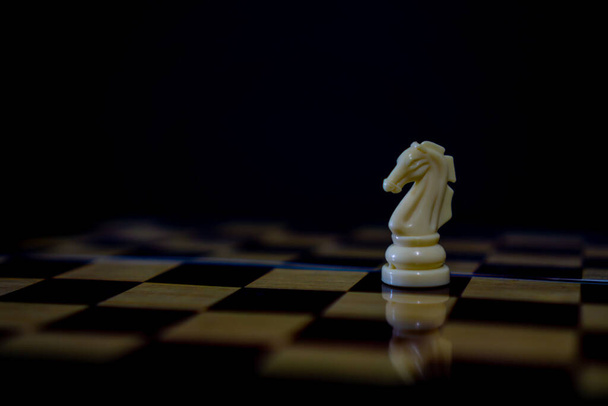 Pieza de ajedrez caballo blanco en tablero de ajedrez marrón - Foto, Imagen