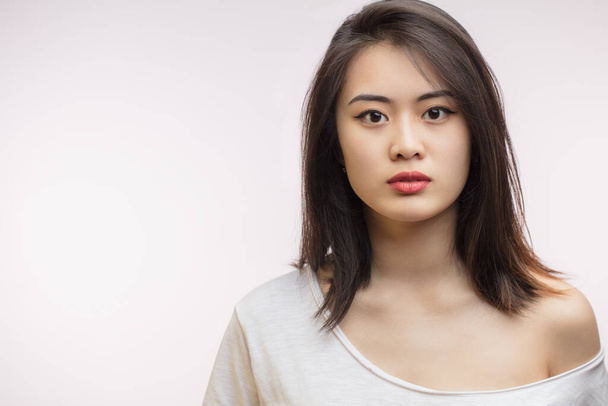 Calm beautiful Asian young woman with loose brown hair, isolated on white. - 写真・画像