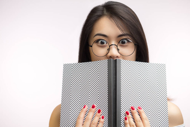 Asian woman feeling shock reading horror story in book, isolated studio shot. - Photo, Image