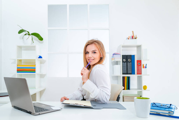 Beautiful young woman working in office. Business people - happy businesswoman or secretary with notebook at office. - Foto, afbeelding