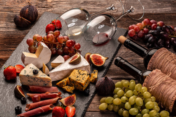 Cheese and cured meat prosciutto with fresh fig, grapes, strawberries and wine, Delicious appetizer, ideal as an aperitif. - 写真・画像