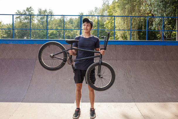 man holding bmx bicycle above head and smiling at camera - Fotografie, Obrázek