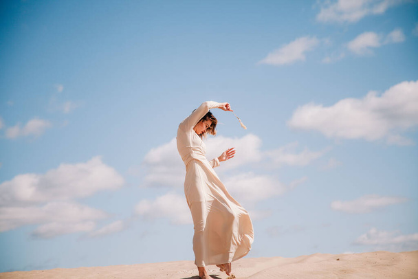 Young, slender girl in beige dress walks in the desert - Foto, Imagem