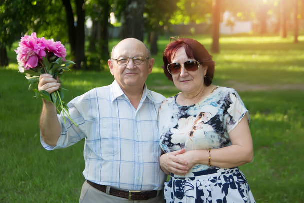Ευτυχισμένο ηλικιωμένο ζευγάρι με ένα μπουκέτο λουλούδια. - Φωτογραφία, εικόνα