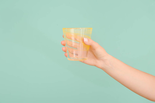 Hand with empty glass on color background - Foto, immagini