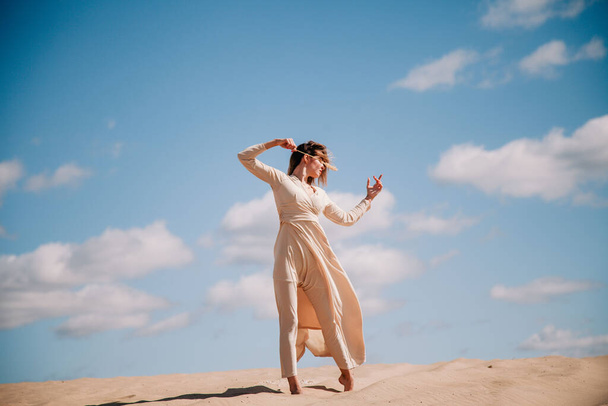 Young, slender girl in beige dress walks in the desert - Foto, immagini
