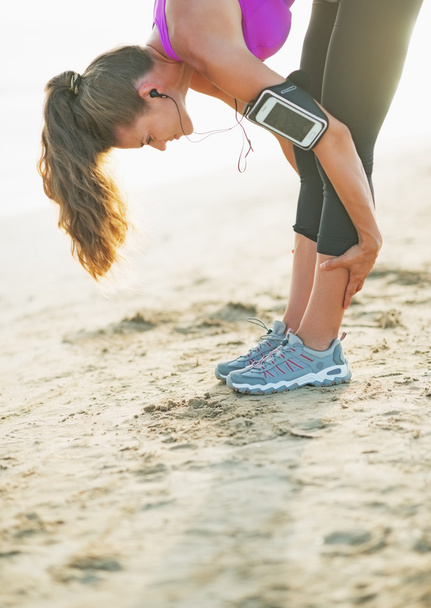 Closeup on fitness young woman stretching on beach - Fotó, kép