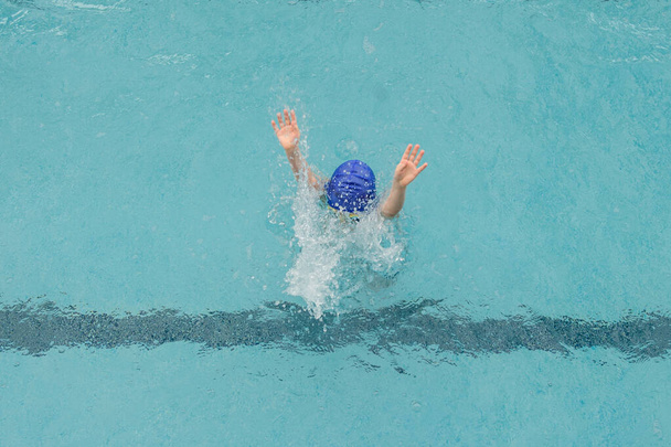 widok z góry 7-letni chłopiec pływanie backstroke w basenie - Zdjęcie, obraz