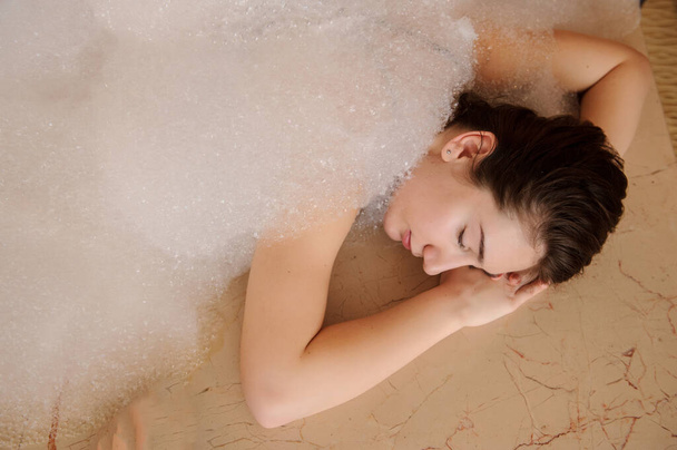 top view of a young woman in white foam relaxing in a hamam - Photo, image