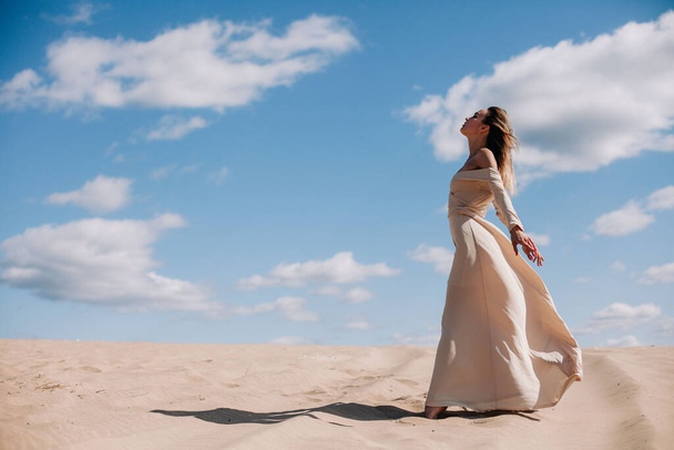 Young, slender girl in beige dress walks in the desert - Zdjęcie, obraz