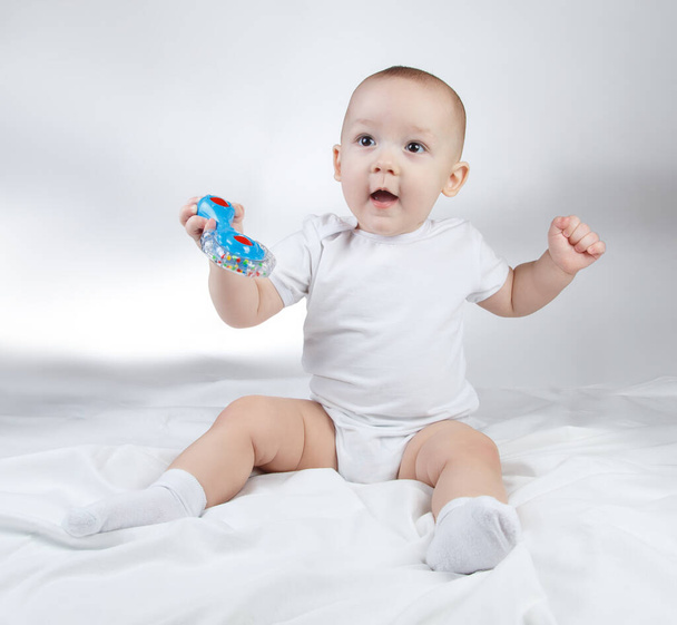 Foto eines zehn Monate alten Jungen mit blauer Rassel - Foto, Bild