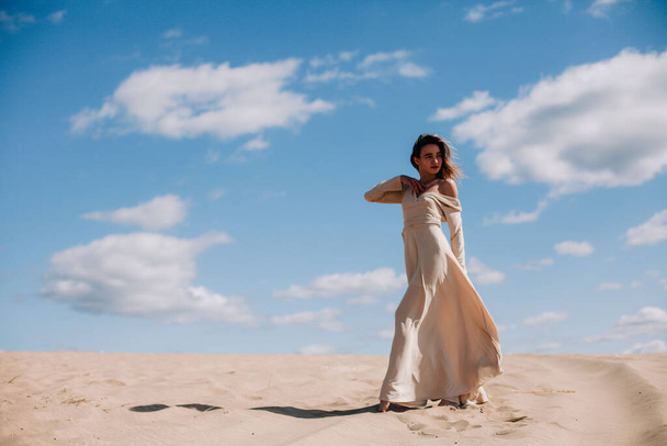 Young, slender girl in beige dress walks in the desert - Zdjęcie, obraz