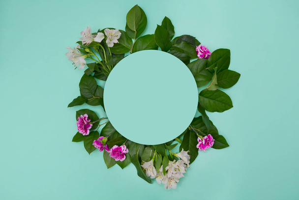 Creative layout made of flowers and leaves with paper card note on  background. Flat lay. Nature concept - Fotoğraf, Görsel