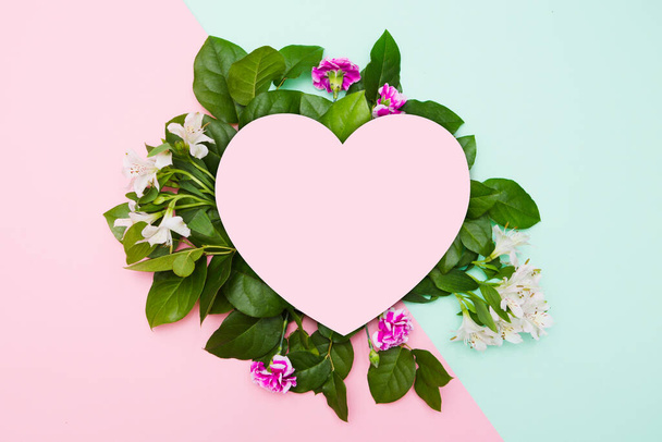 Creative layout with flowers, leaves and paper heart on pastel  background. holiday concept. Flat lay, top view. with St. Valentine's Day - Fotó, kép