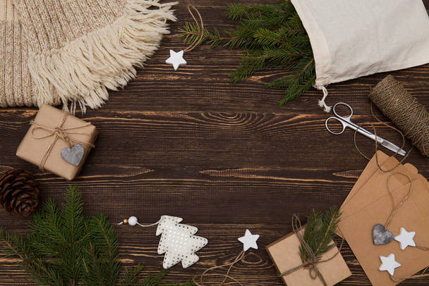 Zero waste, eco friendly Christmas, crafted gifts, natural Christmas decorations, woolen scarf, pine branches on a wooden table. Flat lay, top view, text on white paper. Handmade Christmas presents - Foto, afbeelding