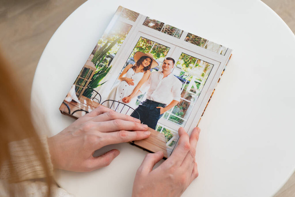 woman hold in hands photo book from family pregnancy photo shoot. - Φωτογραφία, εικόνα