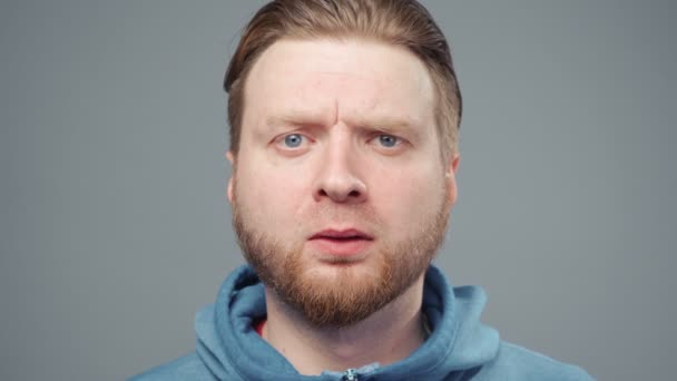 Video van een bange blonde man in een blauwe sweater, portret - Video