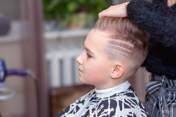 Vista lateral Niza chico europeo conseguir peinado en barbershop.hairdresser hace un peinado para un niño - Foto, imagen