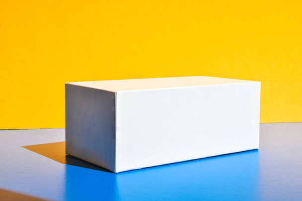 Witte doos. Een drugsdoos model. Mockup. Begrepen, ruimte. Geel en blauw creatief minimalisme isometrische achtergrond. Hard licht. Schaduwen - Foto, afbeelding